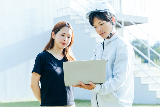 ノートパソコンをもって確認する男女の従業員の写真