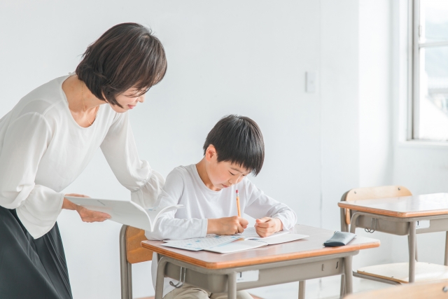 小学生の男の子に学習指導をしている女性の写真