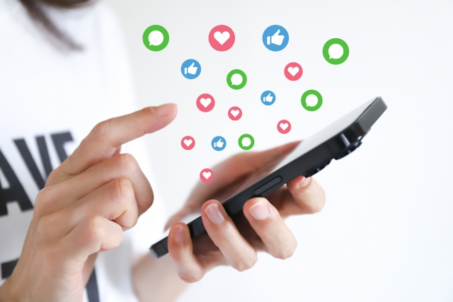 スマートフォンから、良いねやコメント、ハートマークが飛び出しあふれた写真