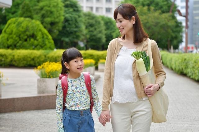 仲良く手をつないで歩く小学生の女の子と母親の女性