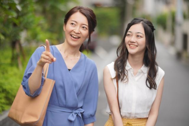 前方を指さす女性と笑顔の女性